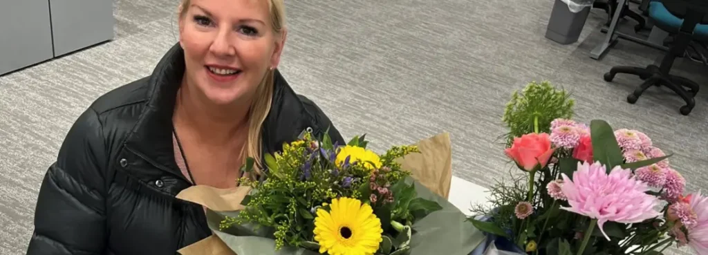 A image of Anna Sills former Managing Director of ADVANCE holding flowers